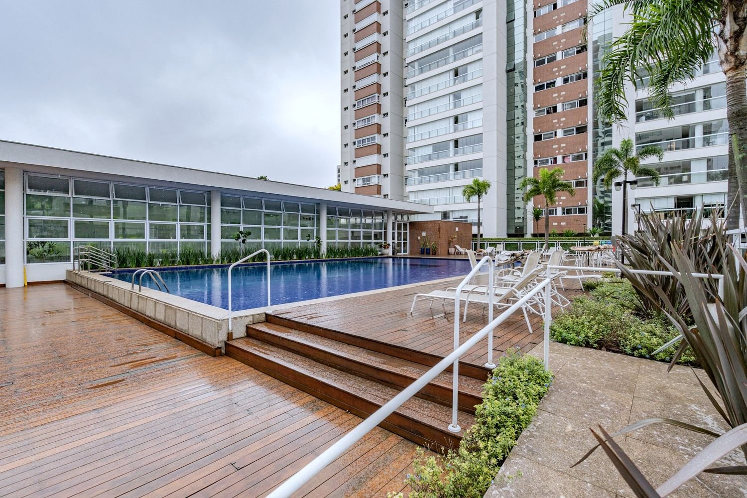 Piscina com deck de madeira e jardins